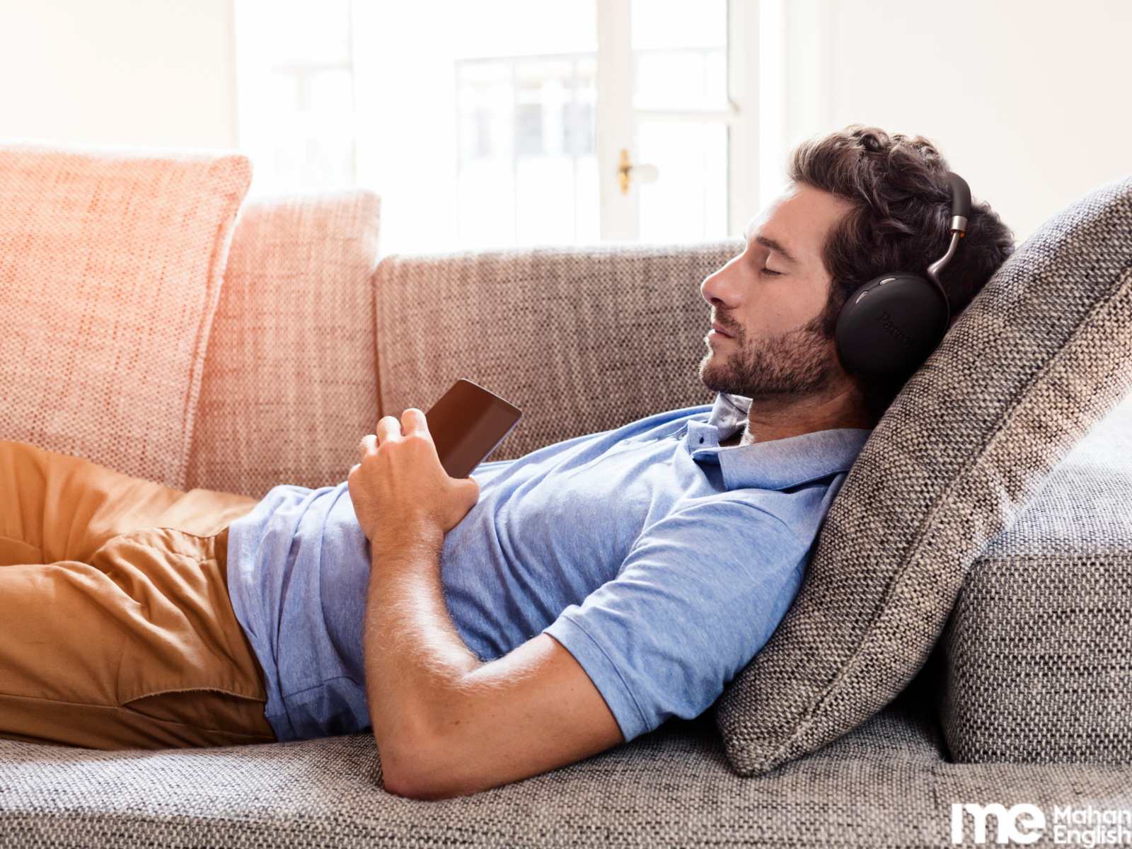 مردی در خواب روی کاناپه در حال گوش دادن به زبان انگلیسی